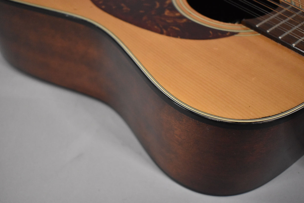 Close-up of the guitar's lower bout, showing the light wood top, dark brown sides, and a tortoiseshell pickguard.