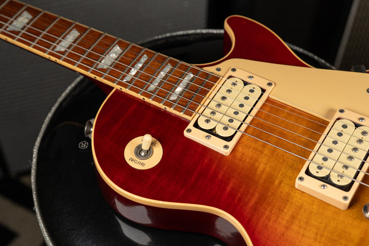 The cherry sunburst body, with two cream humbuckers and a cream pickguard, is shown from the upper bout to the bridge.