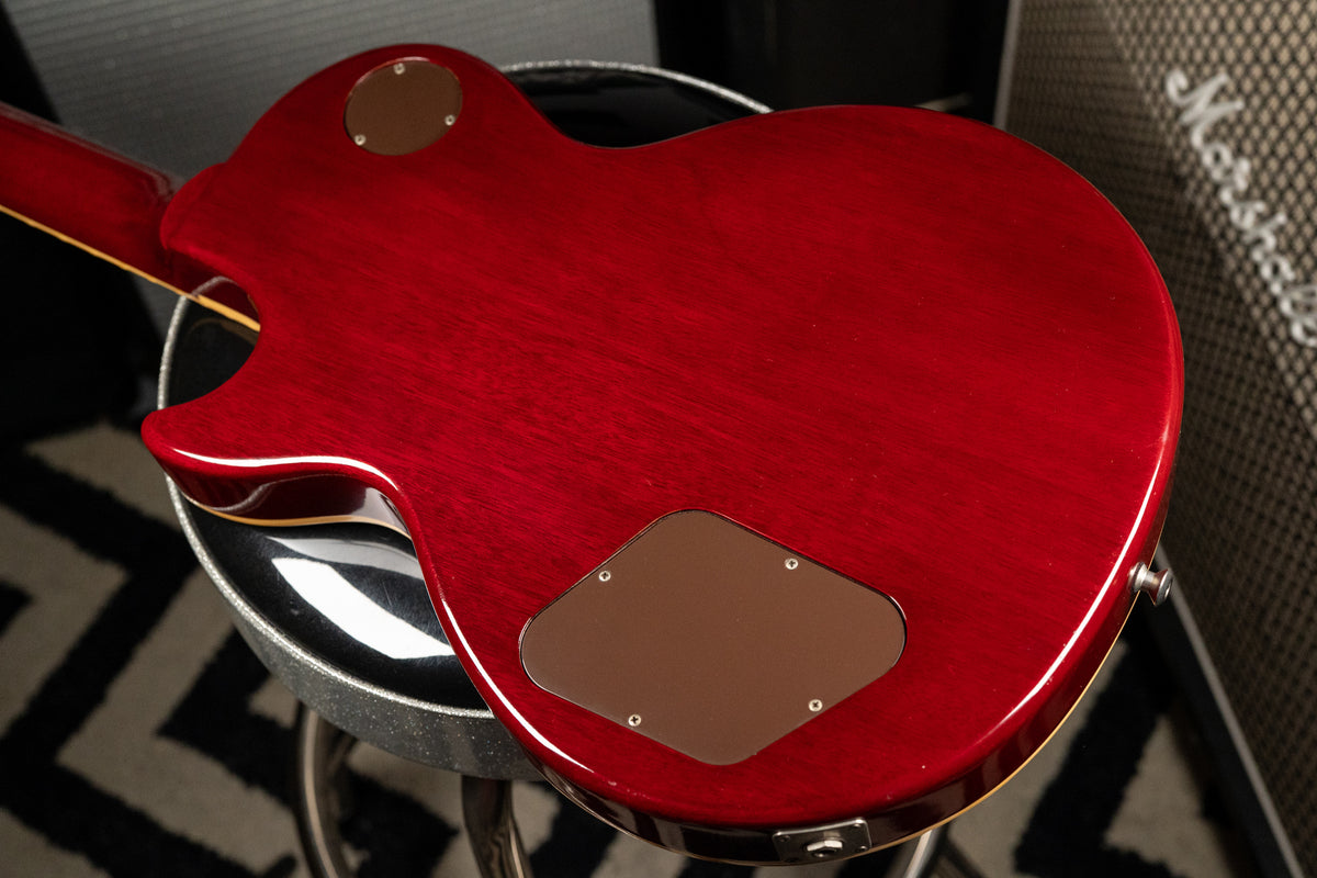 The back of a cherry sunburst guitar, showing the deep red finish, control cavity cover, and strap button.