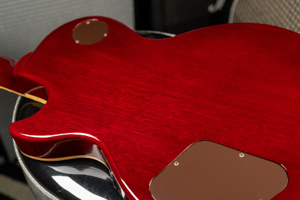 The guitar's cherry red back shows wood grain, light surface scratches, and two brown control cavity covers.