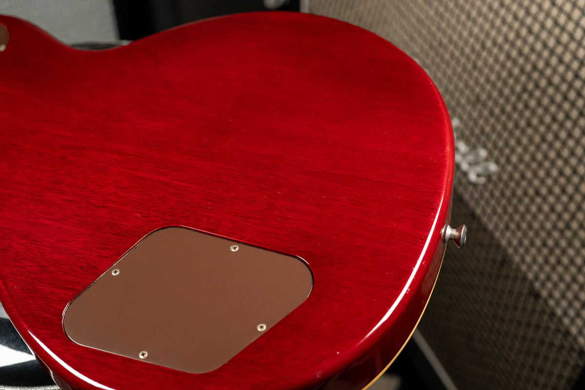 The guitar's cherry sunburst back, showing wood grain and a brown control cavity cover, has light wear and a strap button.