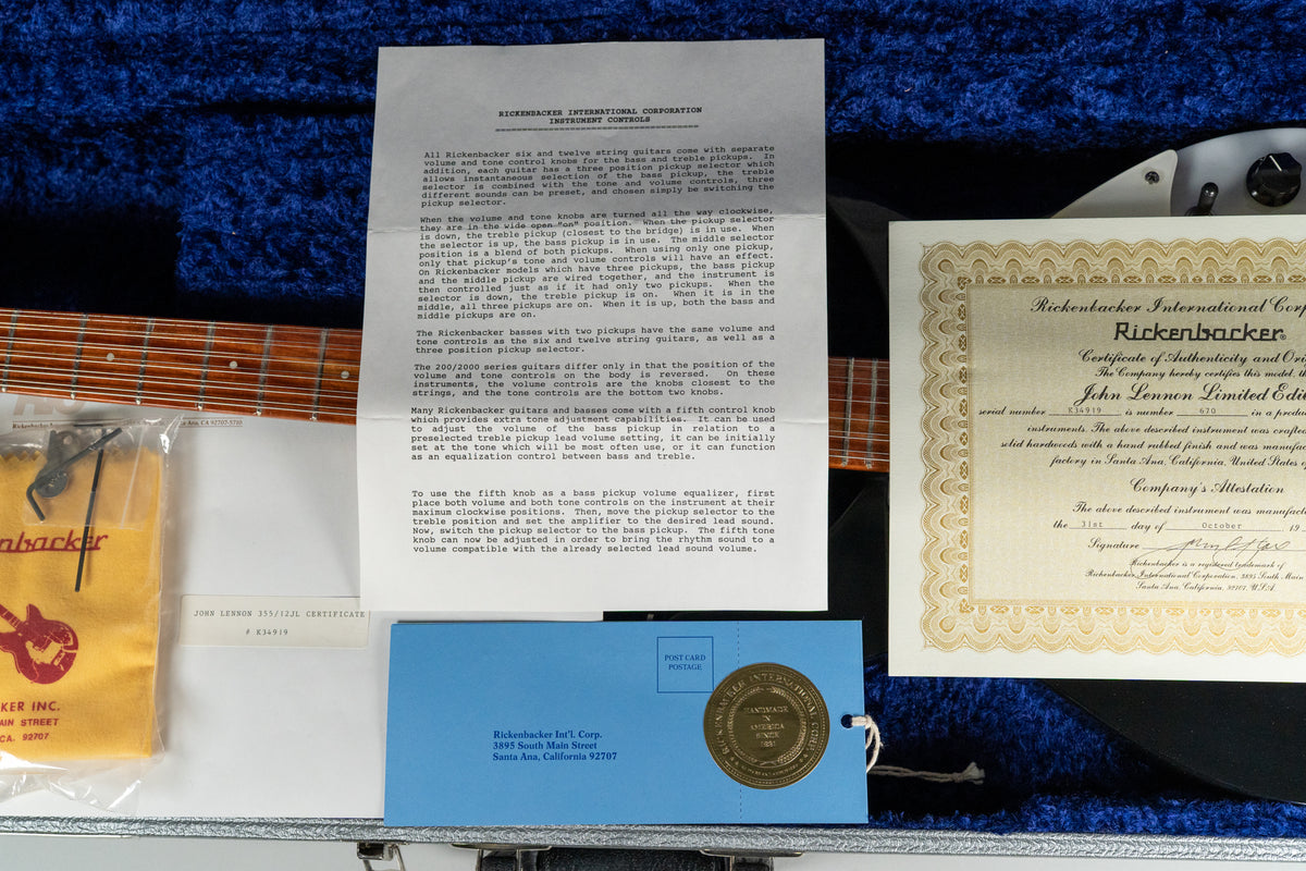 A guitar's fretboard and accessories are visible in a plush blue case, with a certificate and instruction sheet.