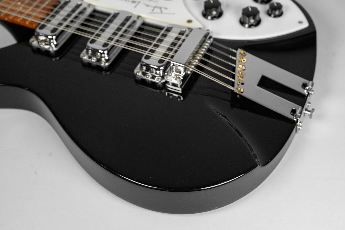 Close-up of the glossy black body and chrome hardware of a 12-string electric guitar, showing the bridge, pickups, and control knobs.