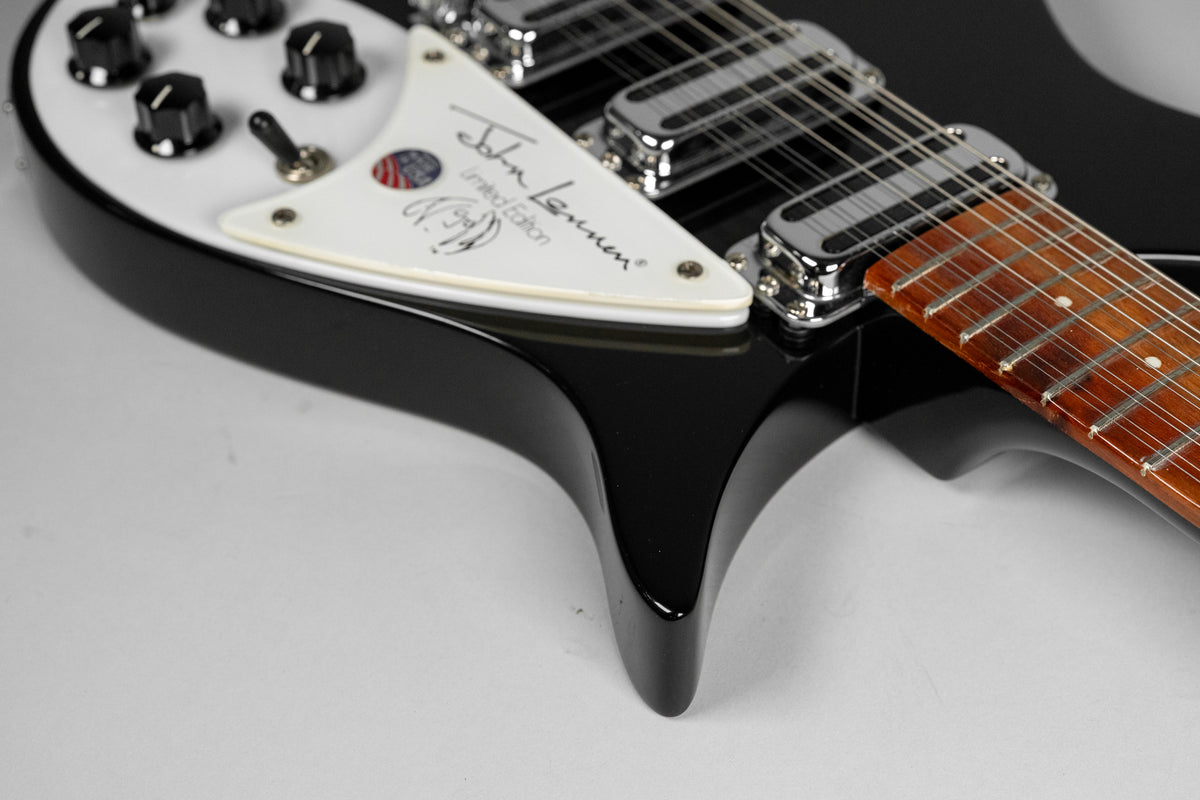 Close-up of the glossy black guitar body, showing the white pickguard with "John Lennon Limited Edition" script, chrome pickups, and dark fretboard.