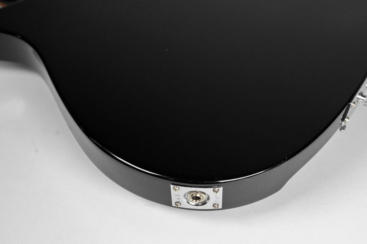 A close-up of the black guitar body, showing the input jack on the lower bout.