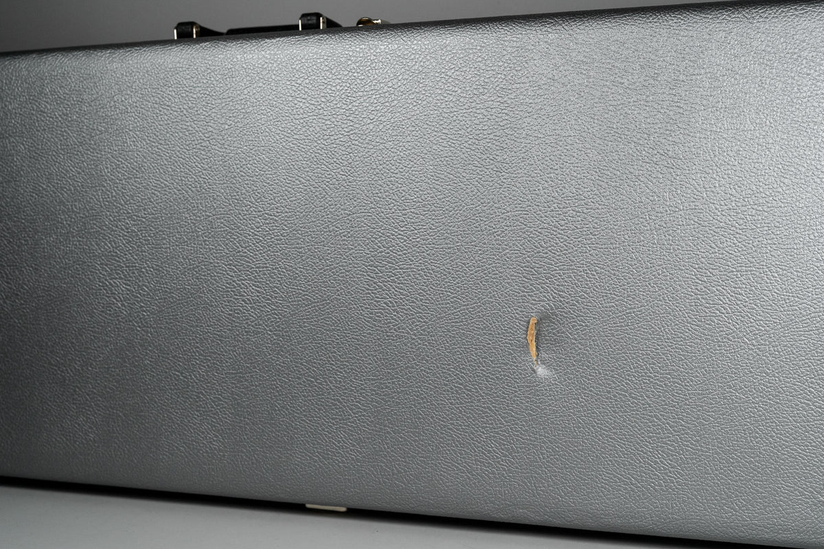Close-up of the black textured hard case, showing a small tear in the covering near the bottom right, revealing lighter material underneath.