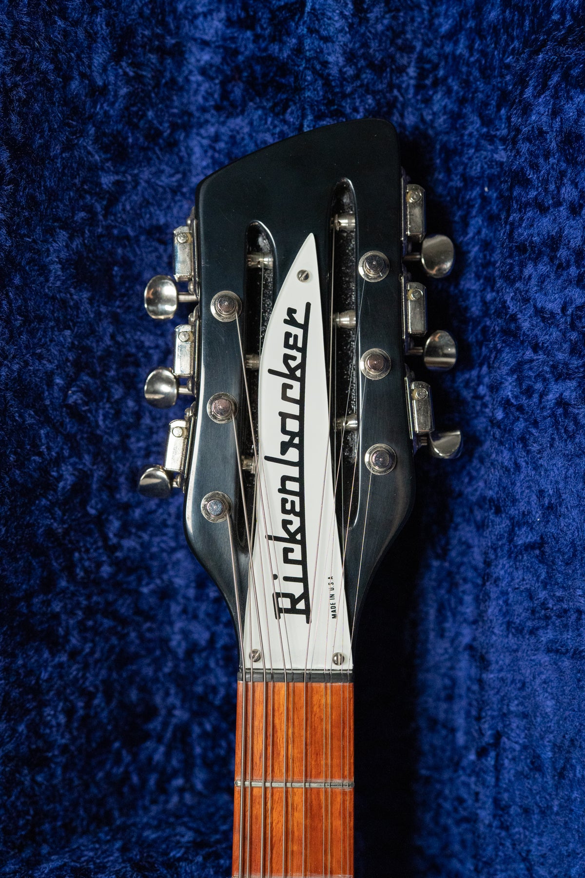 Close-up of the black gloss headstock with a white truss rod cover, chrome tuners, and the top of the fretboard.