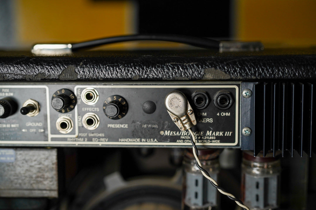 Close-up of the amp's black rear panel, showing controls, jacks, a metal heat sink, and exposed tubes, with worn black tolex on top.