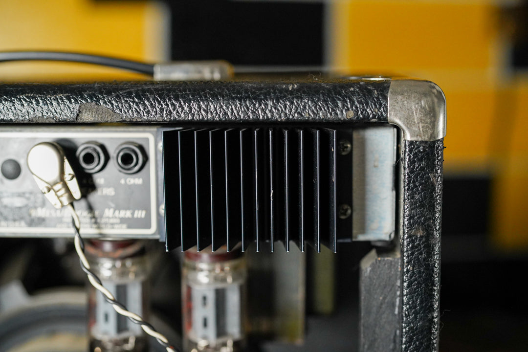 Rear view of the black tolex amp, showing the input panel, a black heat sink, exposed vacuum tubes, and a worn top edge.