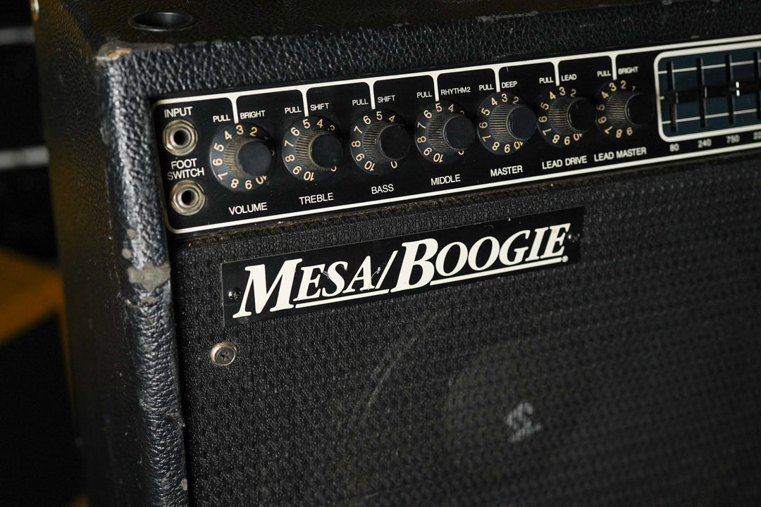 Close-up of the black tolex amp's control panel, showing nine black knobs, two input jacks, and a graphic EQ section.