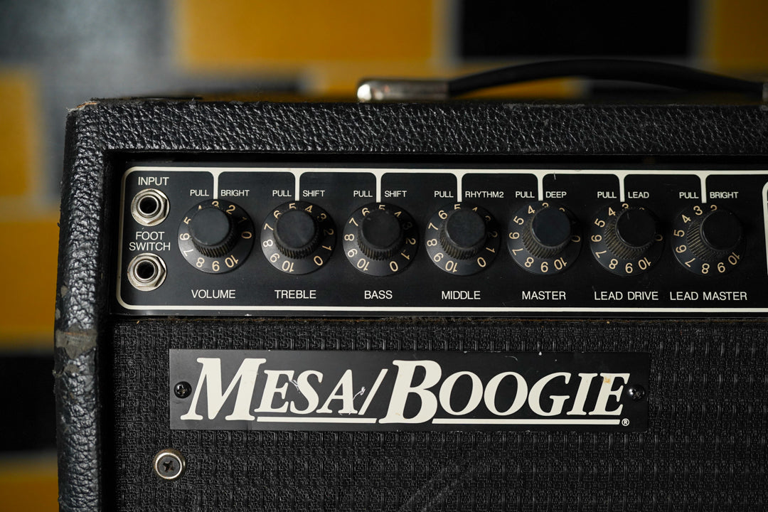 Close-up of the black tolex amp's control panel, showing eight black knobs with white numbers, two input jacks, and some tolex wear.