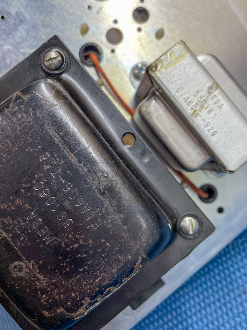 Close-up of the amp's internal components, showing two transformers, one black and worn, the other silver with visible adhesive.
