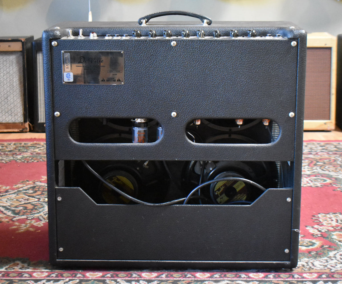 Rear view of a black textured combo amp, showing two visible speakers, tubes, and a metal serial plate.