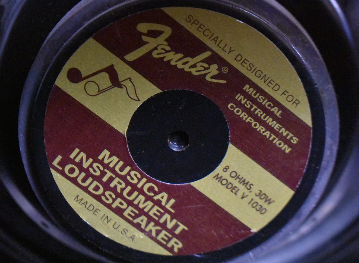 Close-up of the speaker's gold and maroon label with a black center, showing some minor scuffs and dust.