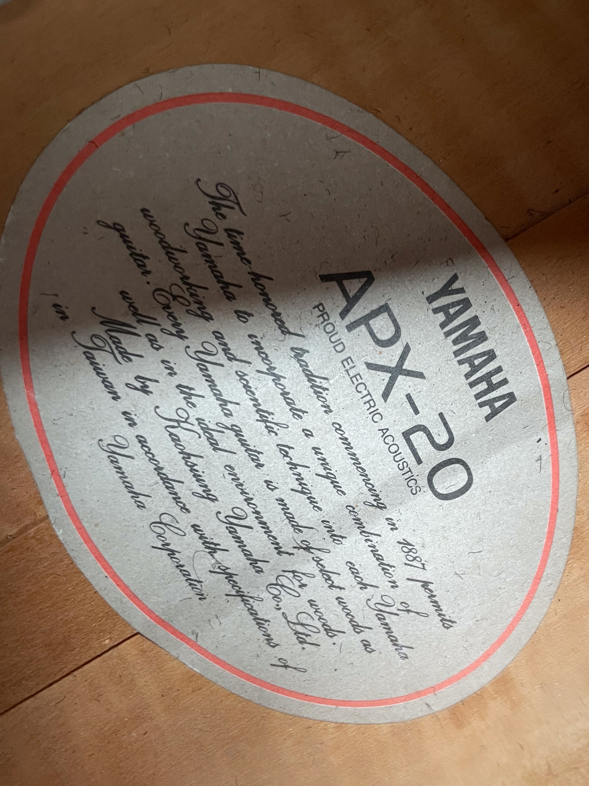 A close-up of the guitar's interior label, a gray oval with a red border, showing text and some dust or fibers.