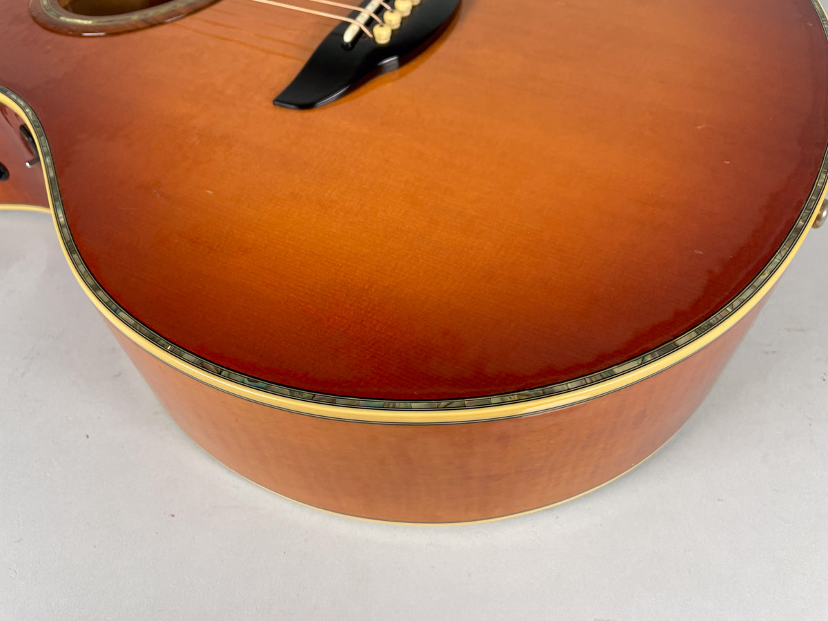 Close-up of the sunburst acoustic guitar's lower bout, showing the glossy finish, abalone purfling, and a few light scratches.