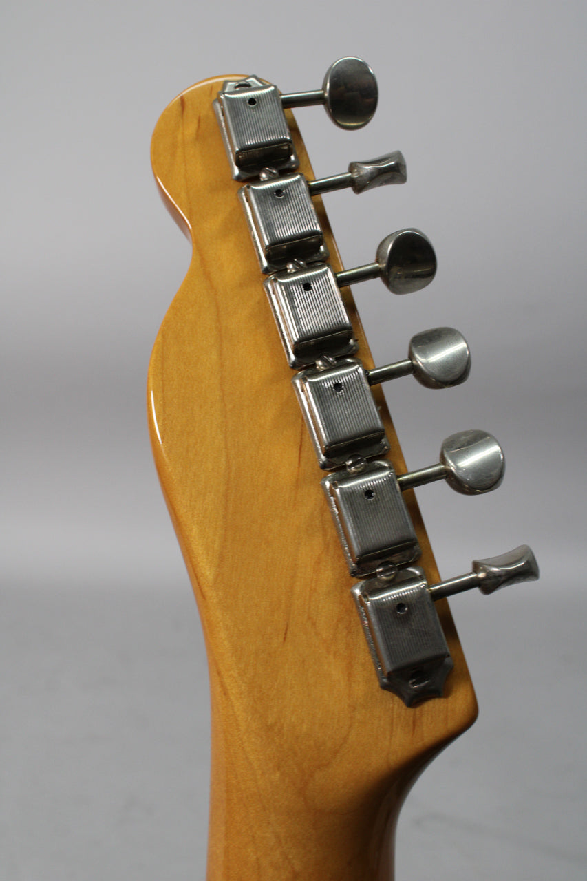 Close-up of the guitar's headstock from the side, showing six chrome-plated tuners with rectangular housings and oval buttons.