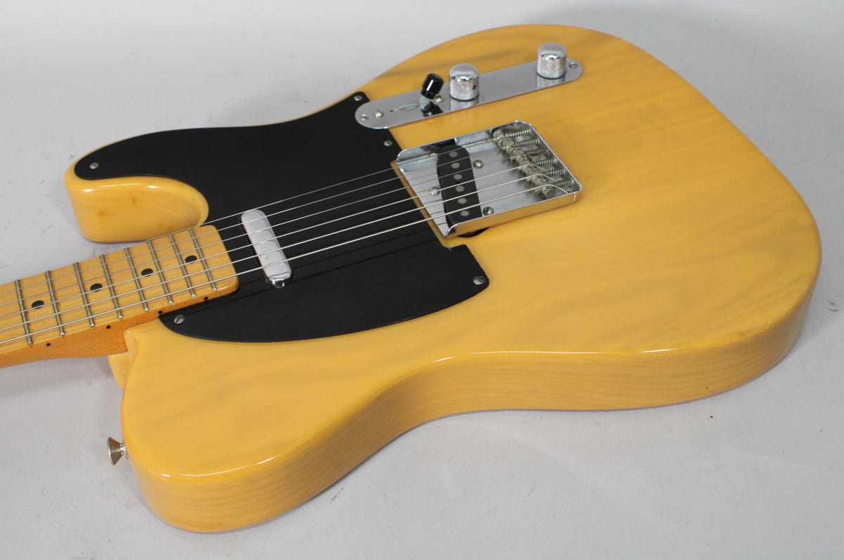Overhead view of a butterscotch blonde Telecaster with a black pickguard, chrome bridge, control plate, and neck pickup cover.