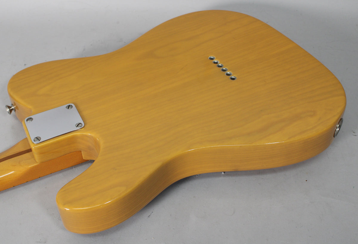 The back of a butterscotch blonde Telecaster body, showing the neck plate, string-through ferrules, and output jack.