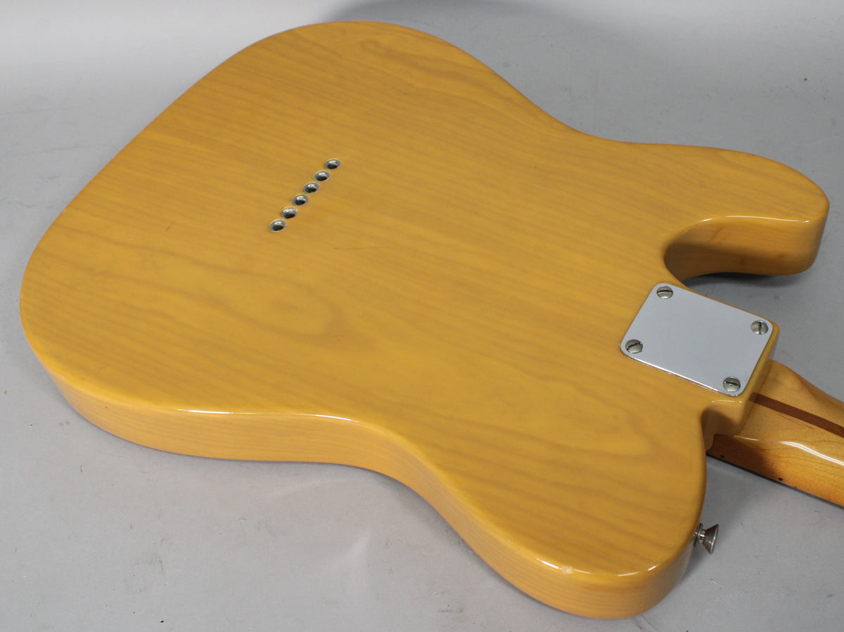 The butterscotch blonde Telecaster body is shown from the back, revealing six string-through-body ferrules and a chrome neck plate.