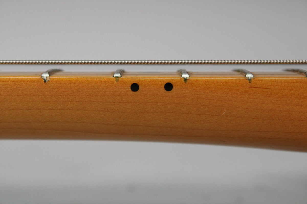 Close-up of the maple neck's side, showing two black dot markers between the 7th and 9th frets, with light wear on the frets.