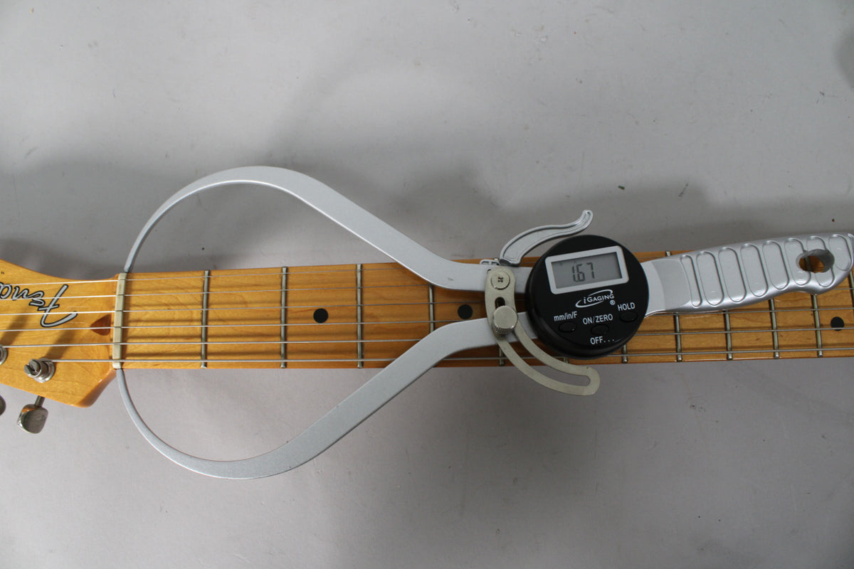 A digital string action gauge measures 1.67mm on the maple fretboard of the Telecaster, showing light wear on the frets.