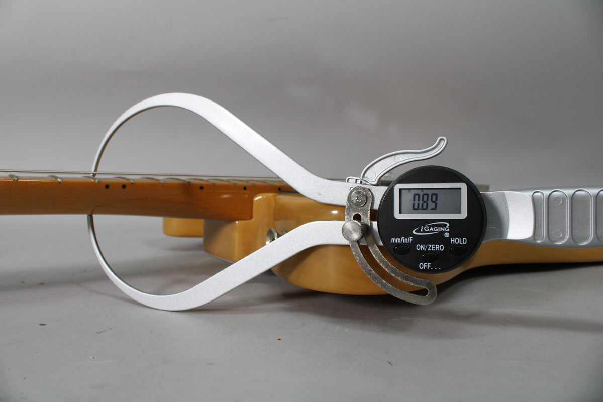 A digital caliper measures the butterscotch blonde Telecaster's neck relief at 0.89, with the fretboard and strings visible.