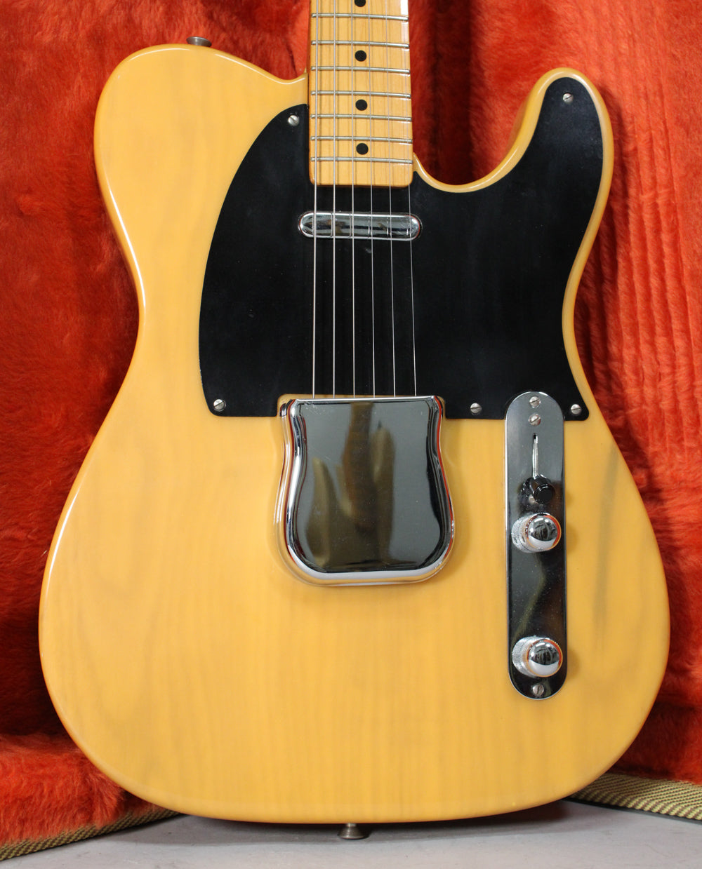 Full body of a butterscotch blonde Telecaster, with a black pickguard, chrome bridge cover, and control plate.