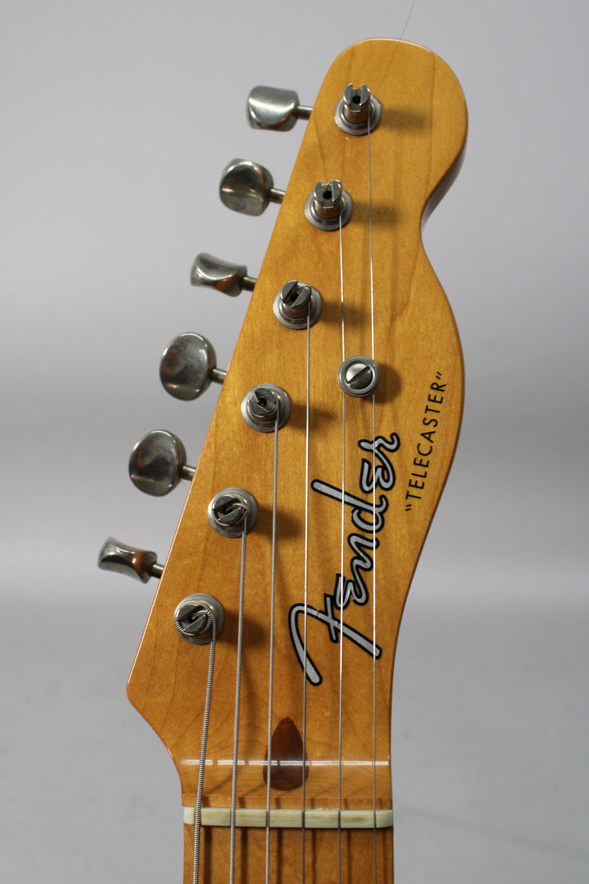 Close-up of the guitar's headstock, showing six chrome tuners, a string tree, and light wear on the maple finish.
