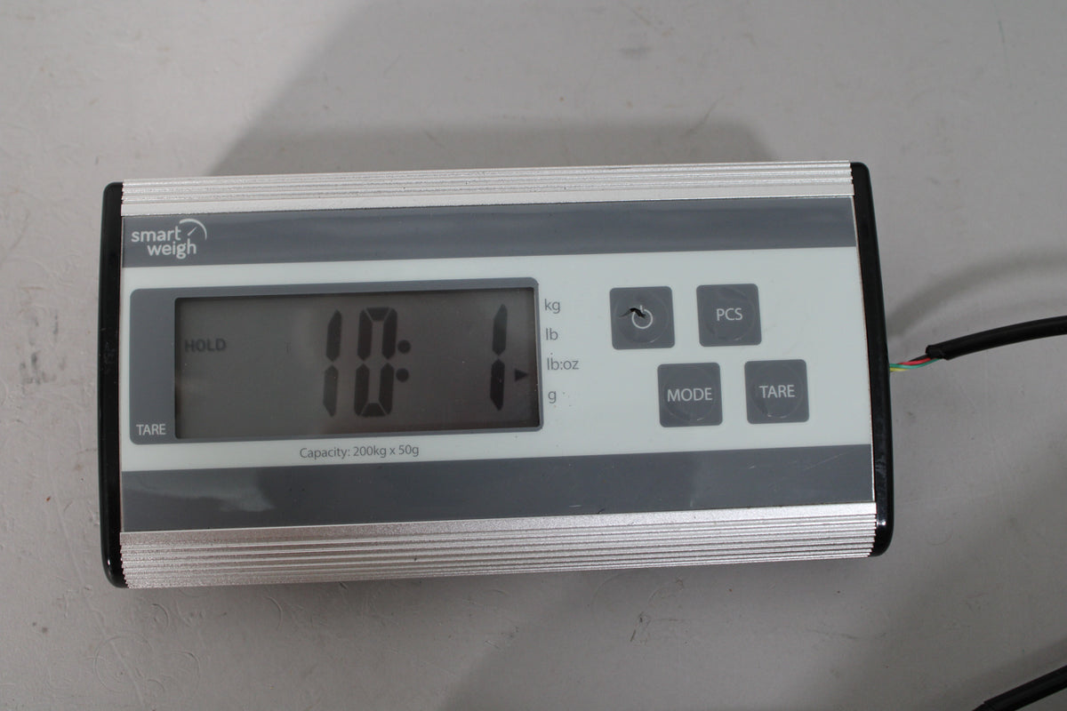Digital scale displaying "10.1" in pounds, with a black cable plugged into the right side.