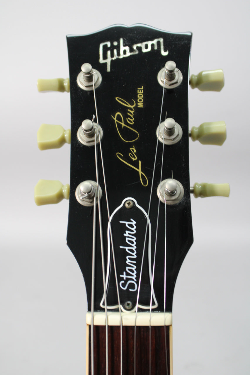 The ebony headstock, with cream tuning pegs and silver hardware, shows some light wear and dust around the tuners.