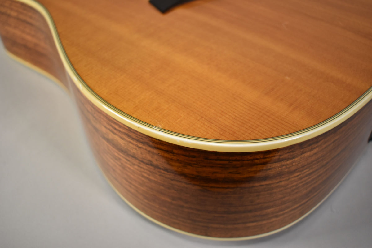 Close-up of the lower bout, showing the light brown top with fine grain and dark brown sides with prominent wood grain, both with cream binding.