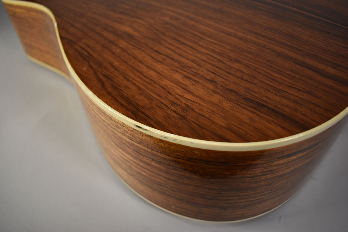Close-up of the lower bout, showing the dark brown wood grain, cream binding, and minor wear along the edge.