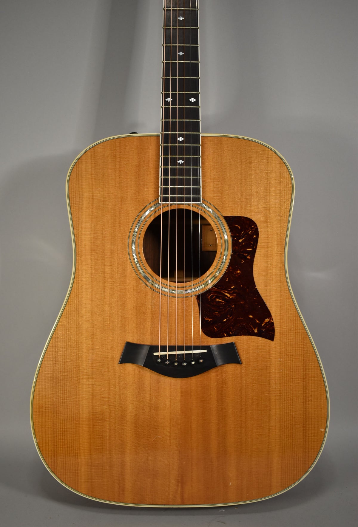 Full front view of a natural finish acoustic guitar with a tortoiseshell pickguard and diamond fretboard inlays.