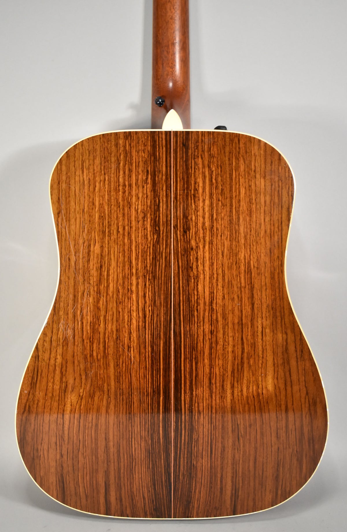 Full rear view of the acoustic guitar, showing the natural wood grain with a center seam and light binding, plus minor surface wear.