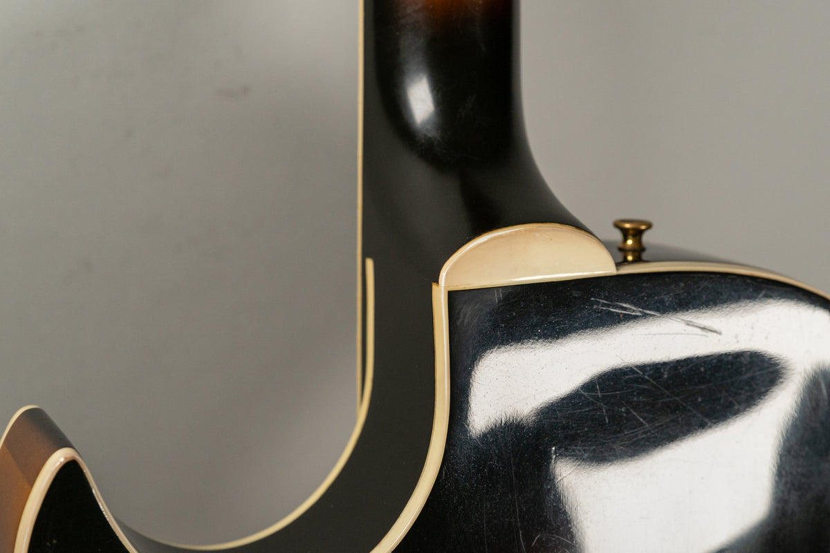 Close-up of the guitar's neck heel and cutaway, showing the sunburst finish, cream binding, and light scratches on the body.