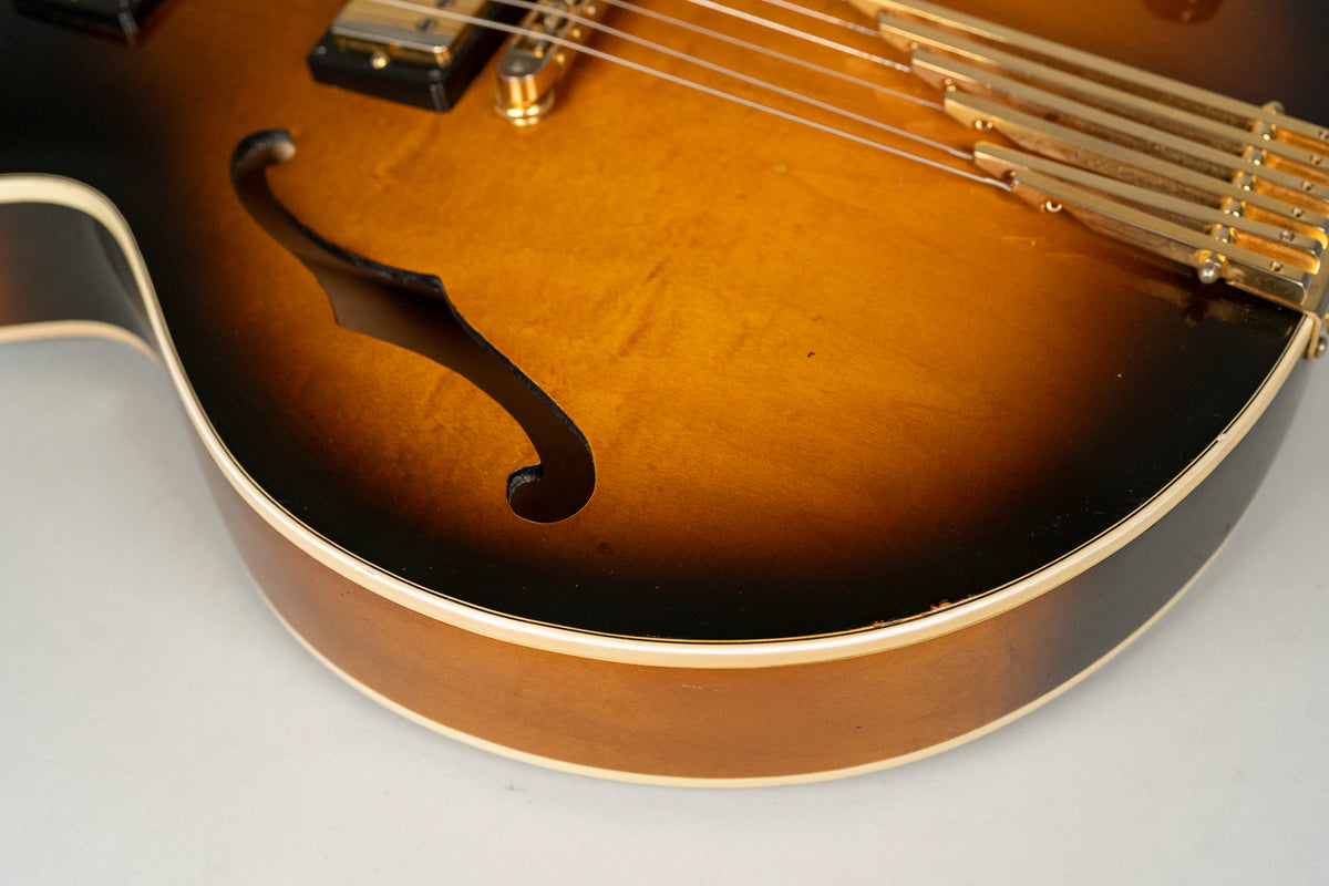 Close-up of the sunburst body, showing the f-hole, gold hardware, and binding with some wear along the lower edge.