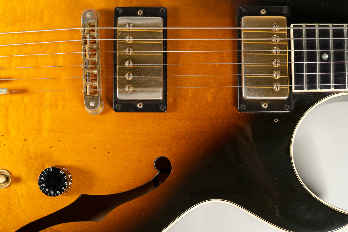 Close-up of the sunburst body, showing two gold humbuckers, a tune-o-matic bridge, a black control knob, and an f-hole.