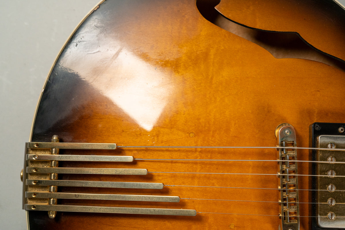 Close-up of the sunburst body with a gold trapeze tailpiece, tune-o-matic bridge, and neck humbucker, showing finish wear.