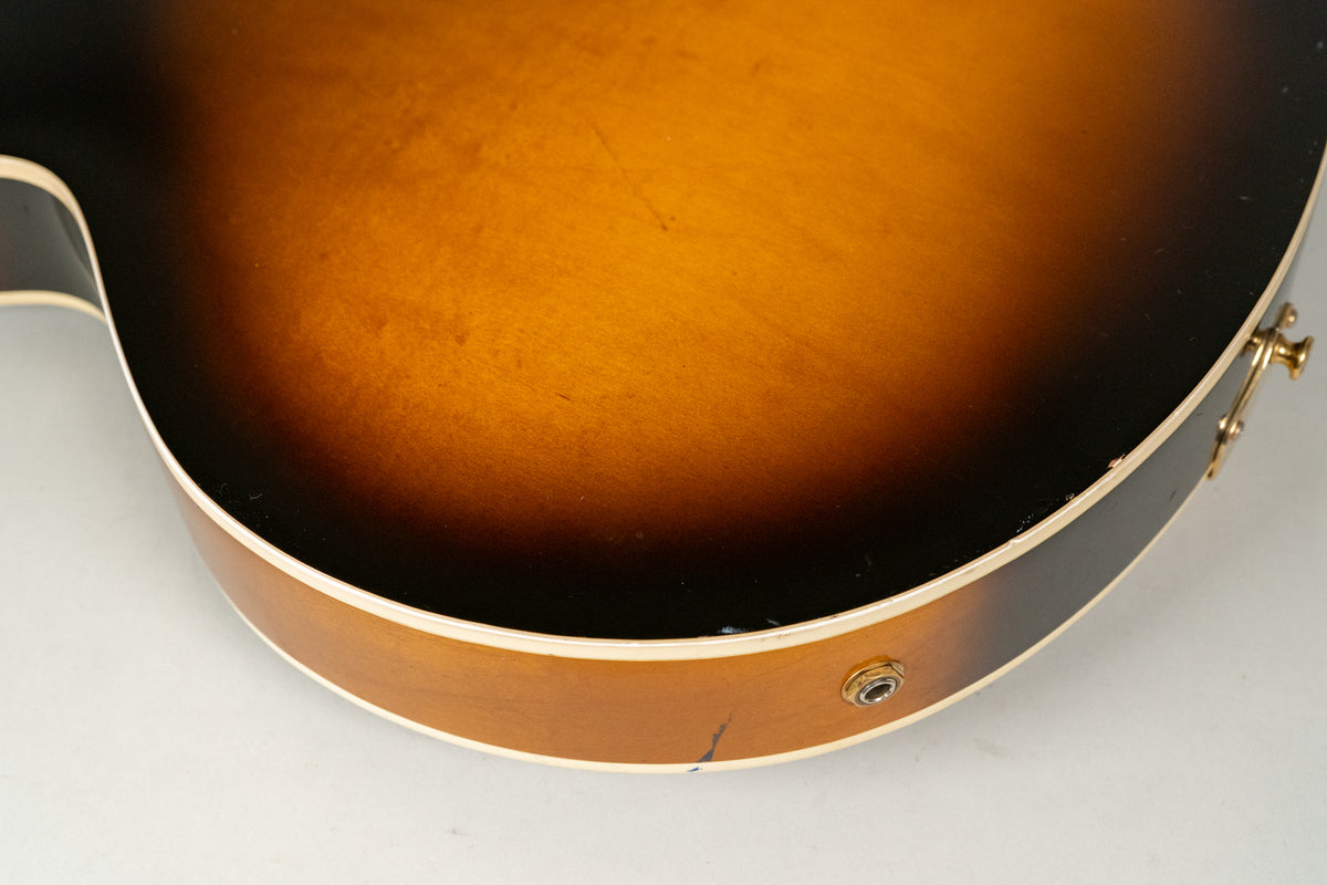 Close-up of the guitar's lower bout, showing the sunburst finish, output jack, and a few minor scratches and dings on the body.