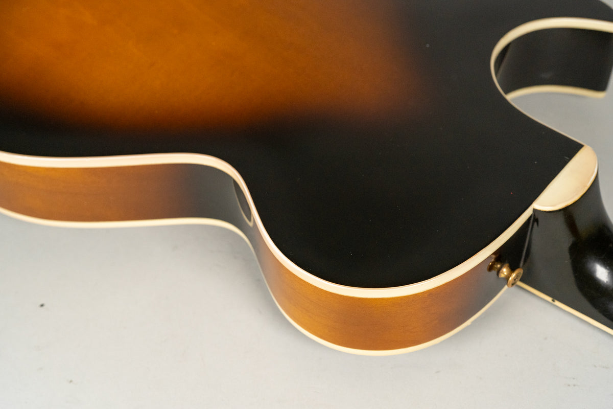 Close-up of the guitar's lower bout, showing the sunburst finish, cream binding, and a gold strap button.
