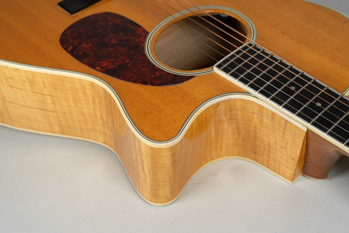 Close-up of the guitar's lower bout and cutaway, showing the natural flame maple sides, tortoise pickguard, and part of the fretboard.