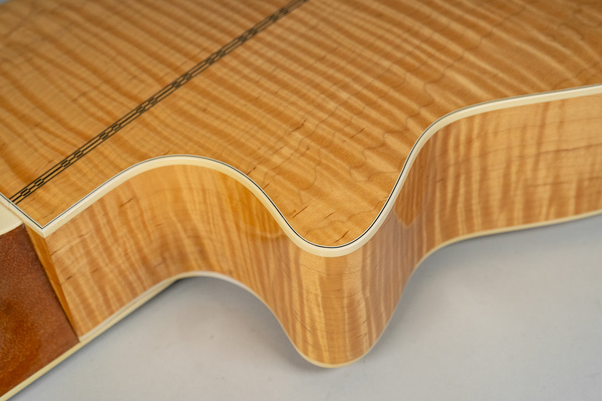Close-up of the guitar's lower bout and cutaway, showing the flame maple back and side with a dark decorative strip down the center.