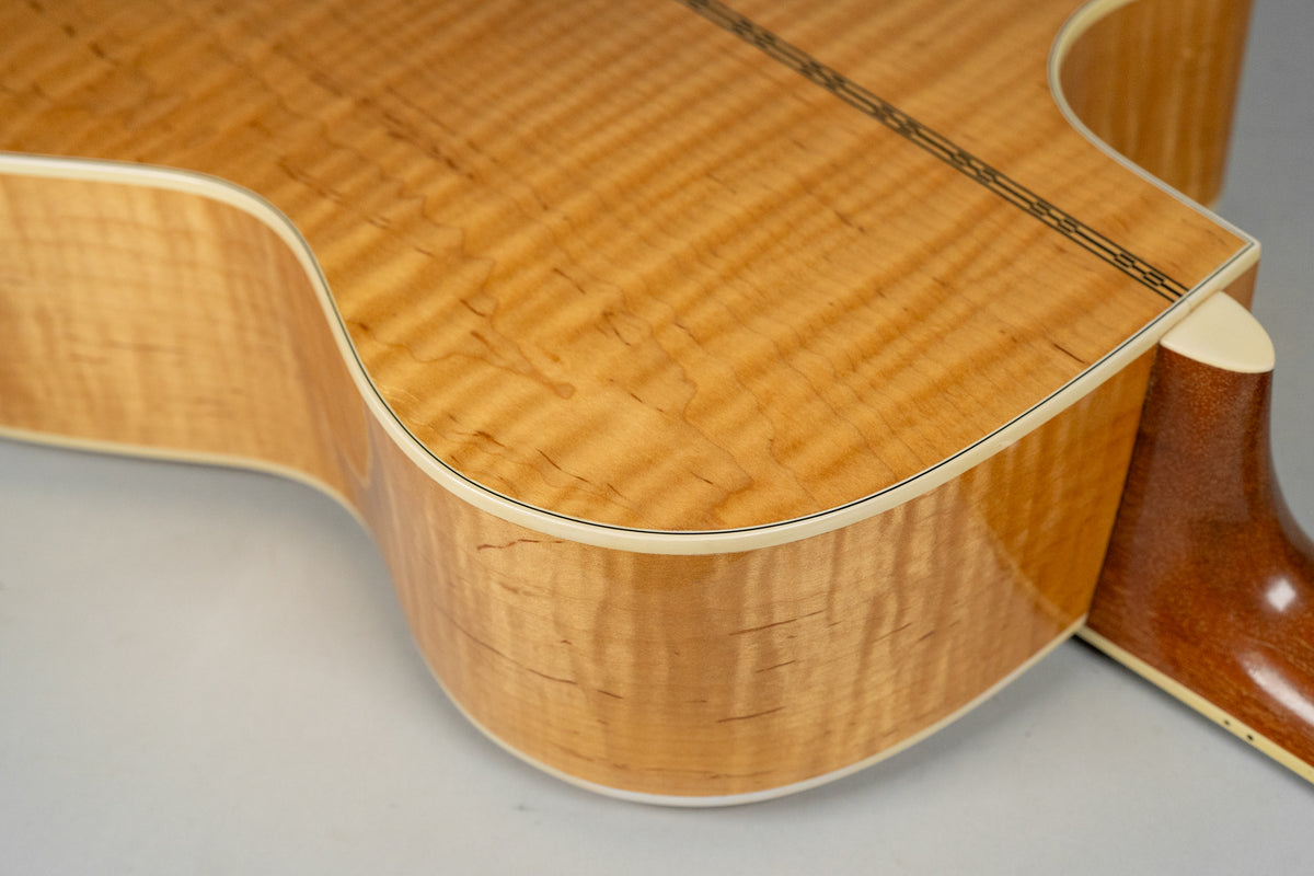 Close-up of the guitar's lower bout and cutaway, showing the flame maple back and sides with light binding and a dark center strip.