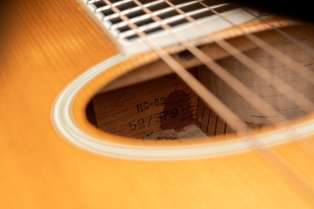 Close-up of the natural finish flame maple body, showing the soundhole with white binding and internal model and serial numbers.