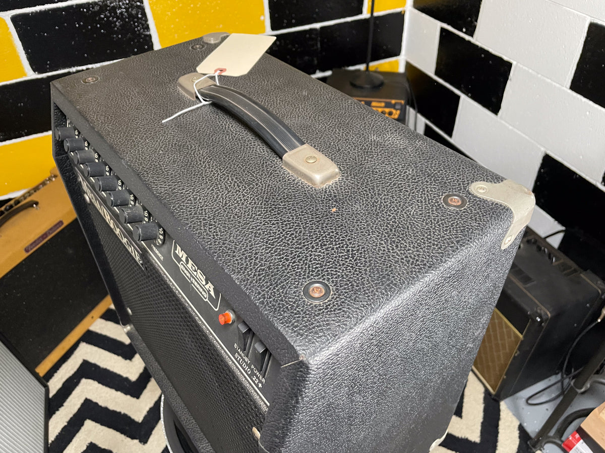 Top-down view of the black textured combo amp, showing the handle, metal corner protectors, and front panel controls with a red power switch.