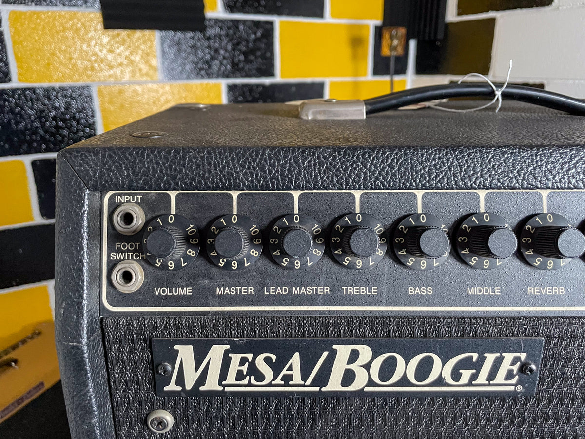 Close-up of the black textured amp's top and front control panel, showing seven numbered black knobs and two input jacks.