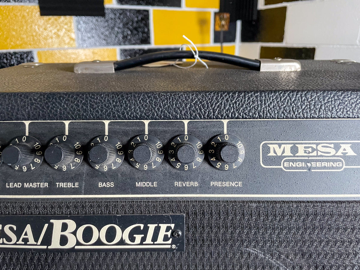 Top-down view of a black textured amp, showing the control panel with six black numbered knobs and a black carry handle.