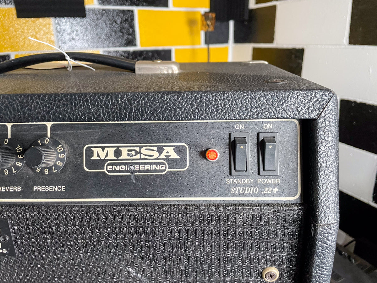 Close-up of the black textured amp's top right, showing two black toggle switches, a red indicator light, and some control knobs.