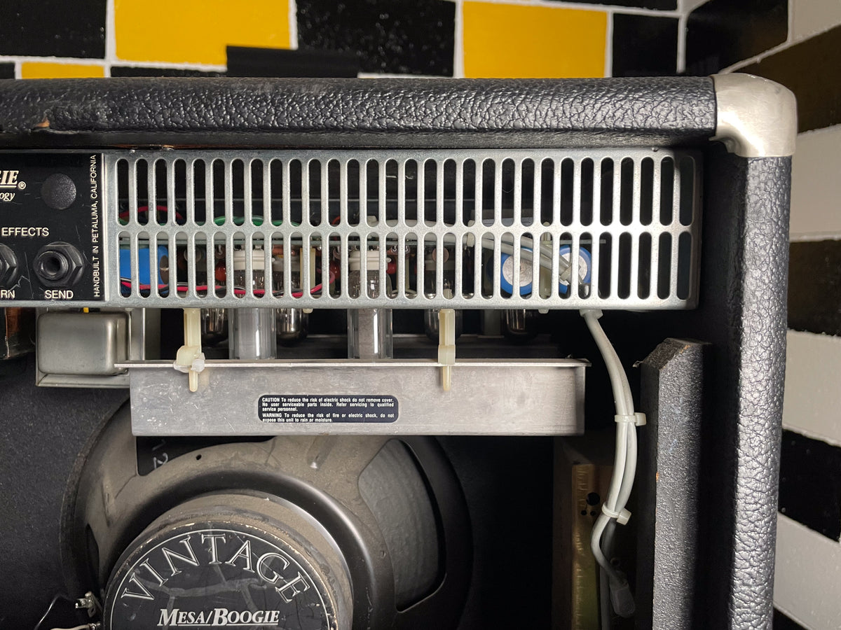 Top-down view of the amp's rear, showing the black textured cabinet, silver corner protectors, and internal tubes behind a metal grate.